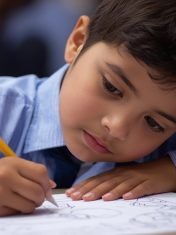 give the image of a students pakistani that is wearing uniform nad performing pencil color activity